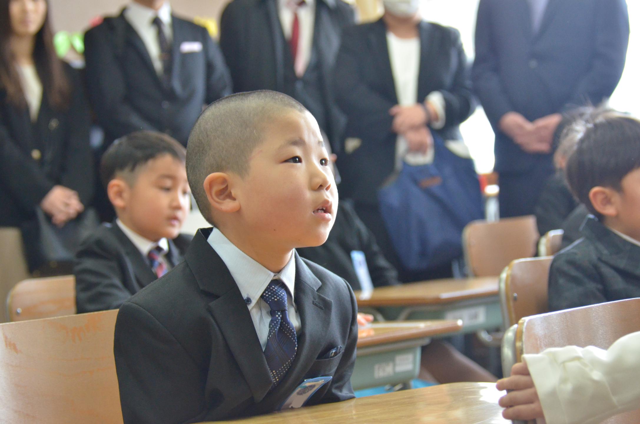 教室で先生の話を聞く新入生