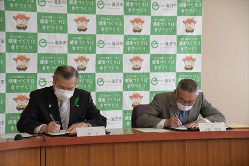 協定書にサインする様子