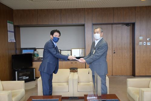 鳥越範夫会長から市長に寄付が行われている様子