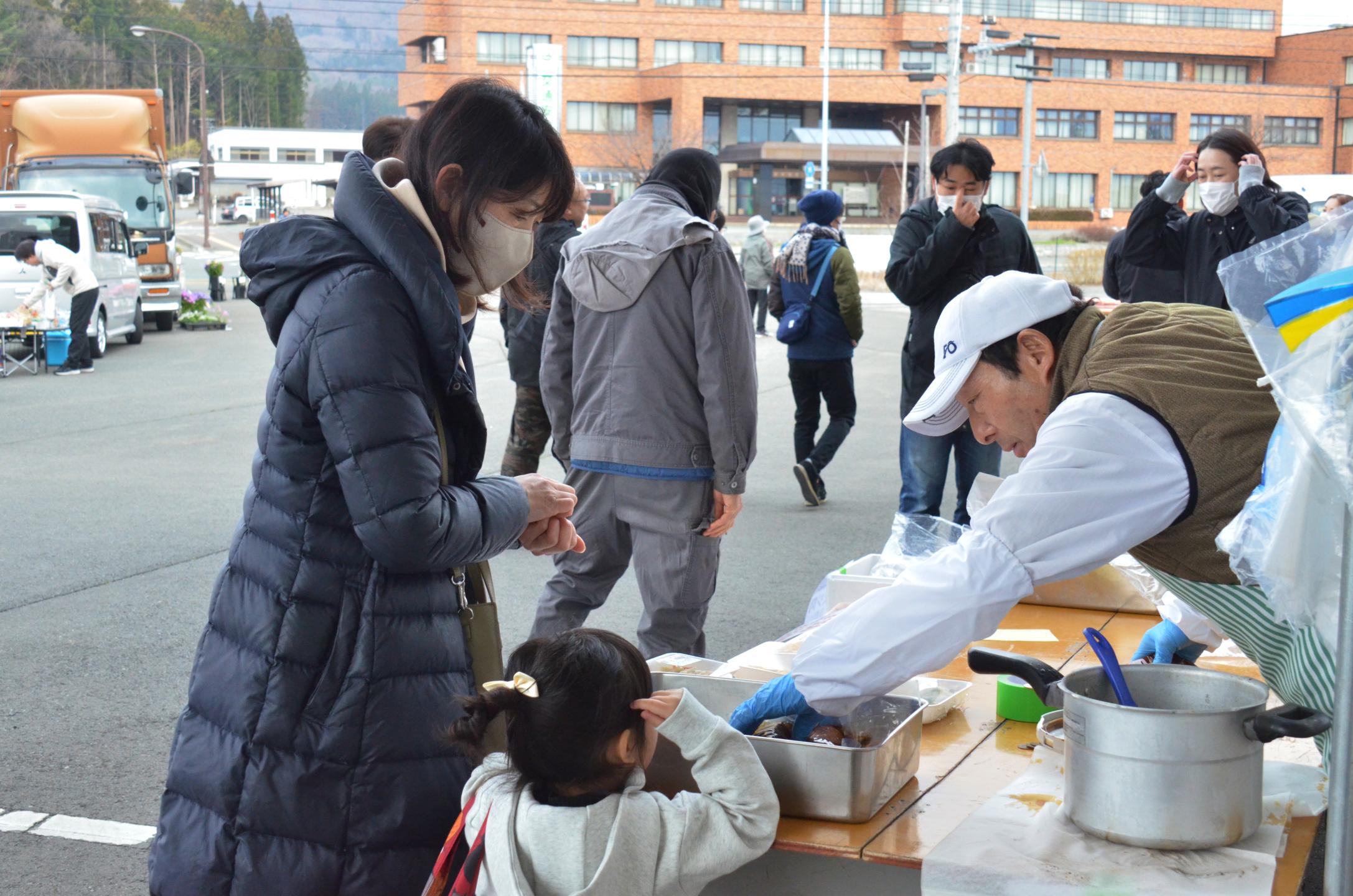 肉を販売する店舗で買い物をする親子
