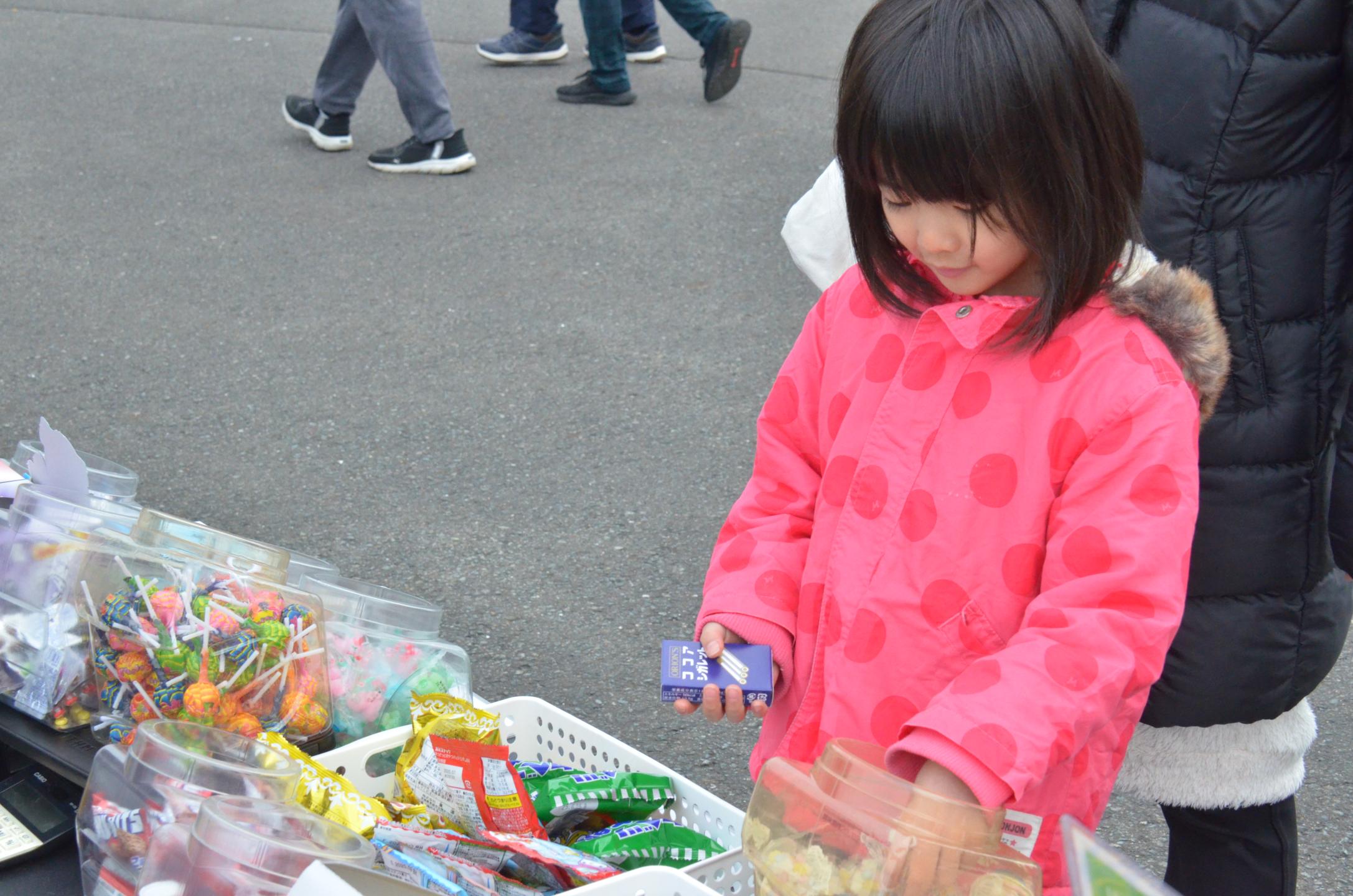 菓子の店舗で商品を選ぶ少女