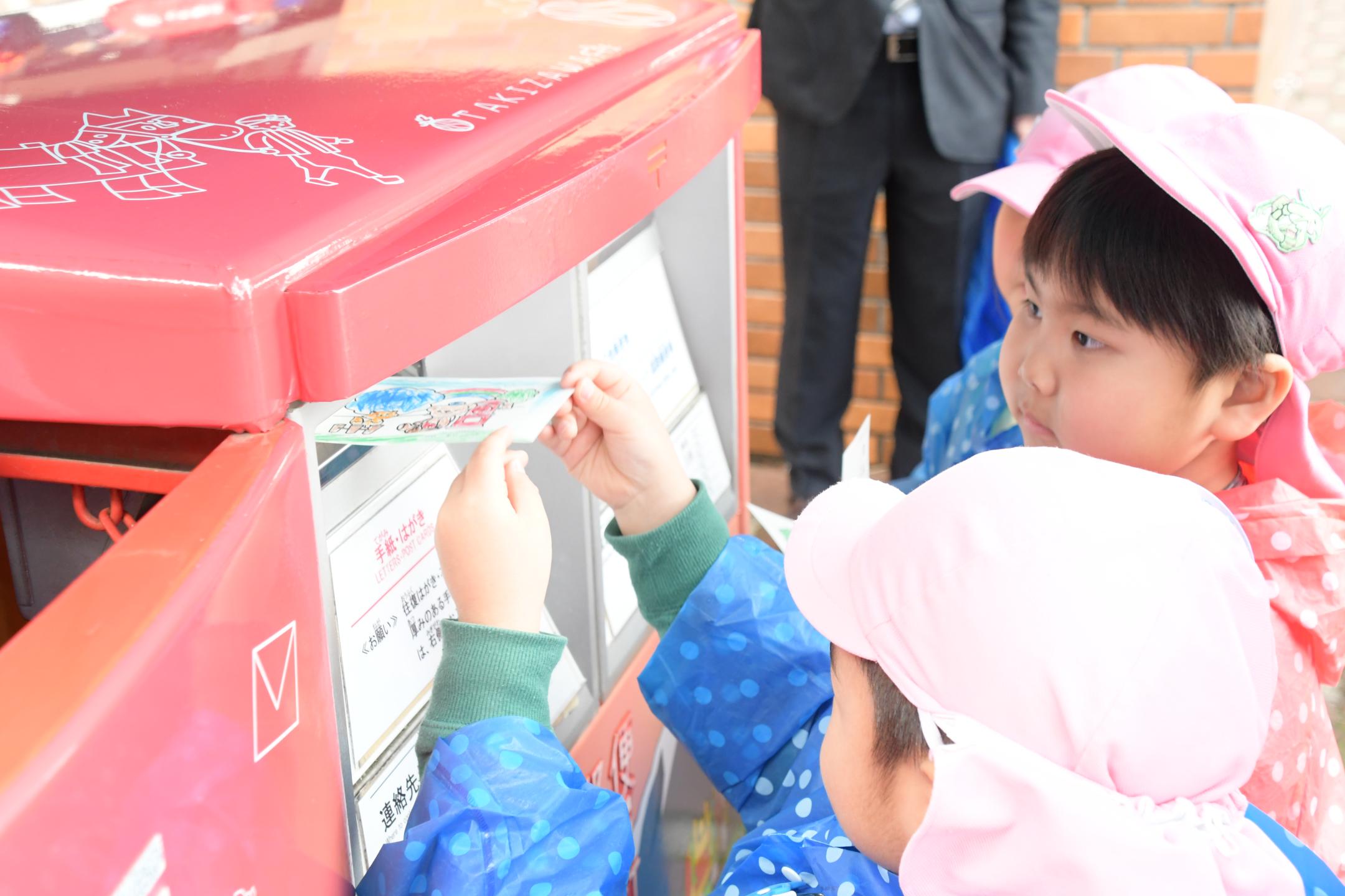 持ち寄ったはがきを投函する園児