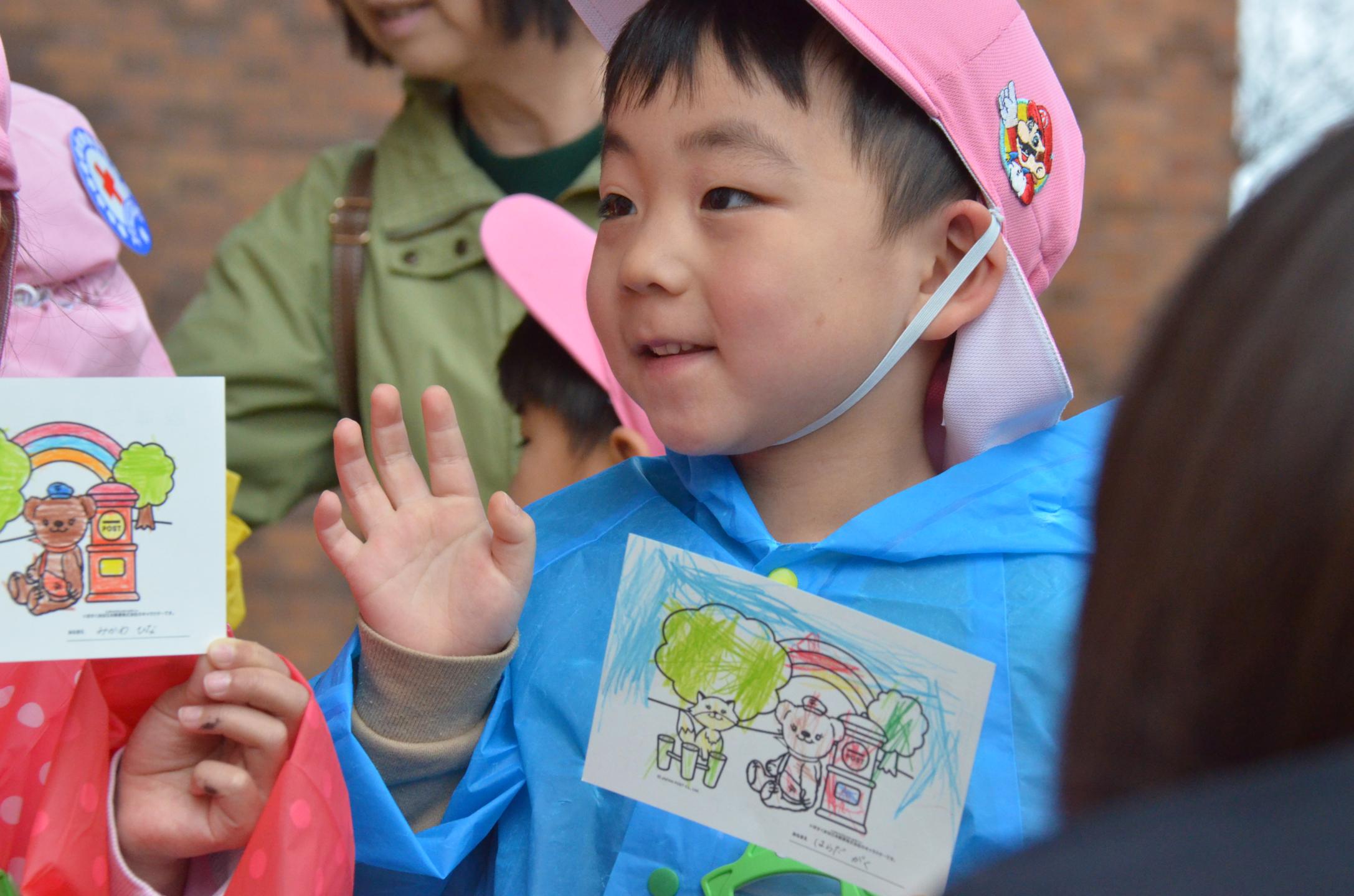 持ち寄ったはがきをちゃぐぽんに見せる園児