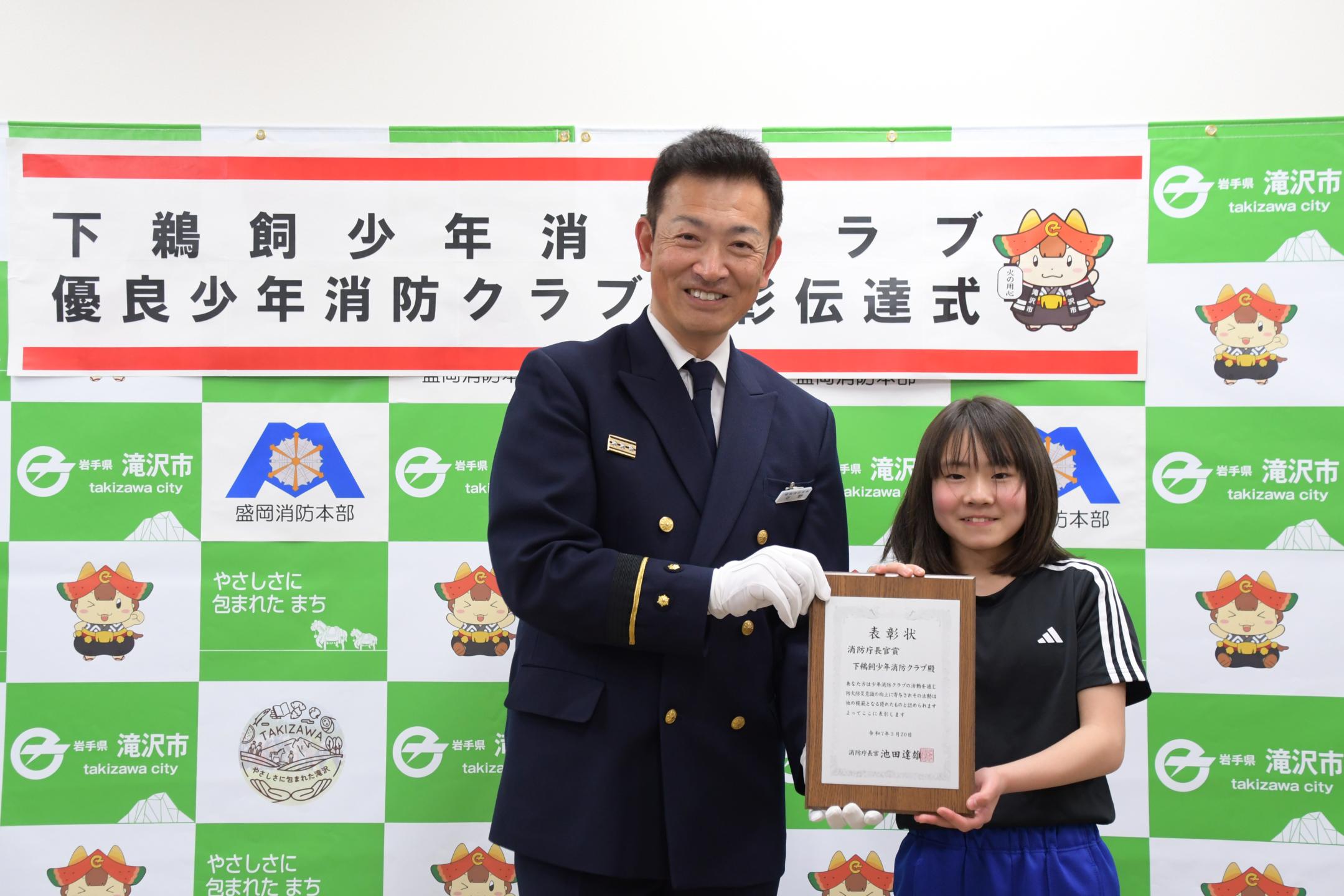 表彰状を手に記念撮影する大川さんと滝沢消防署長