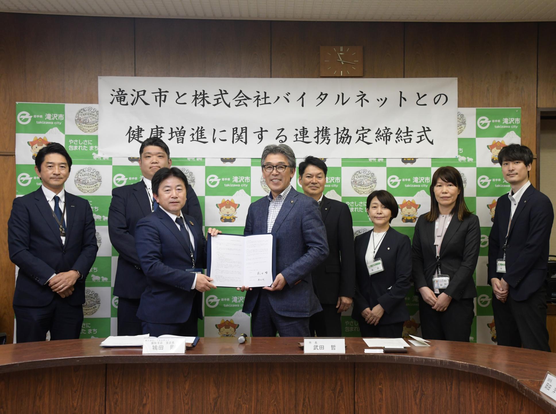 連携協定書と共に記念撮影する関係者