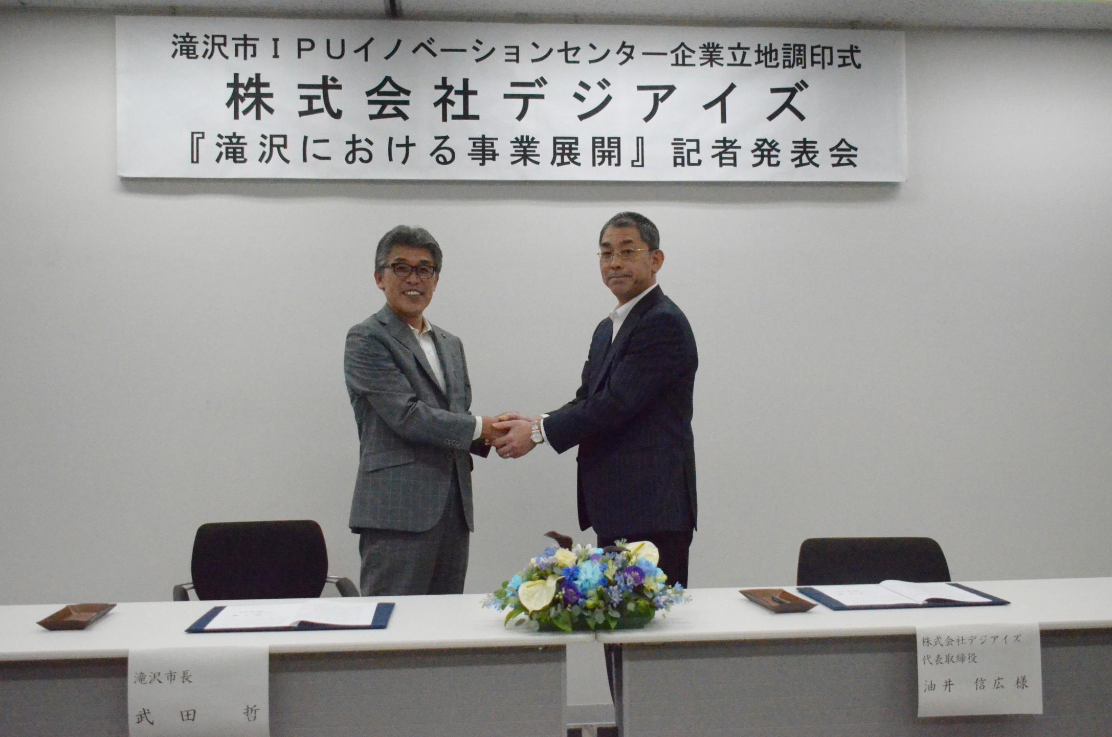 握手を交わす油井代表取締役と武田市長