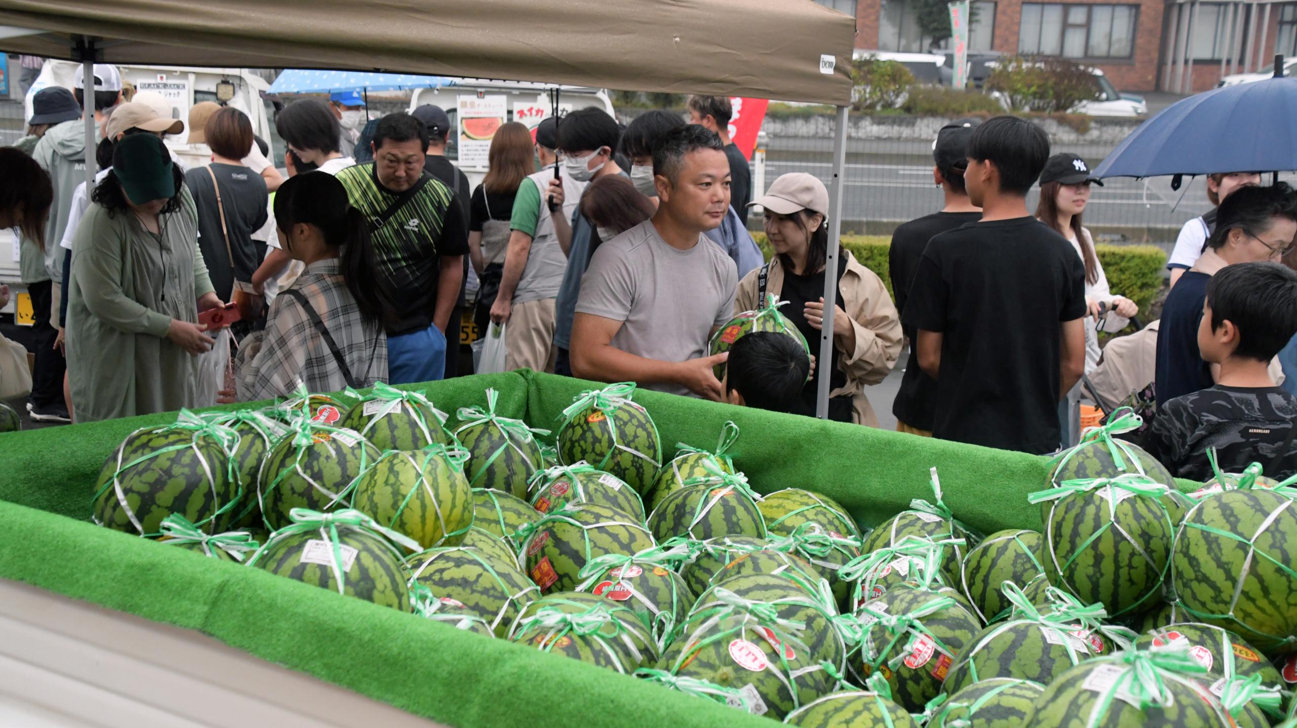 軽トラに積まれた滝沢スイカと吟味する来場者