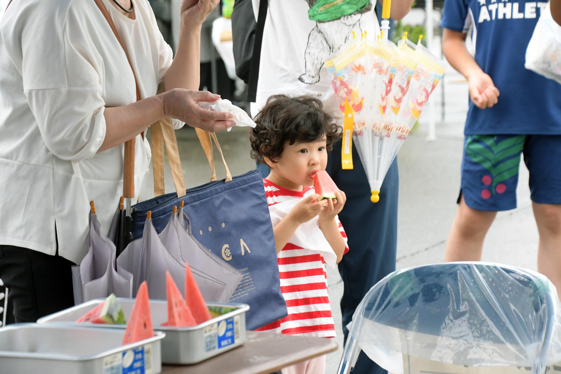 試食のスイカを食べる子ども