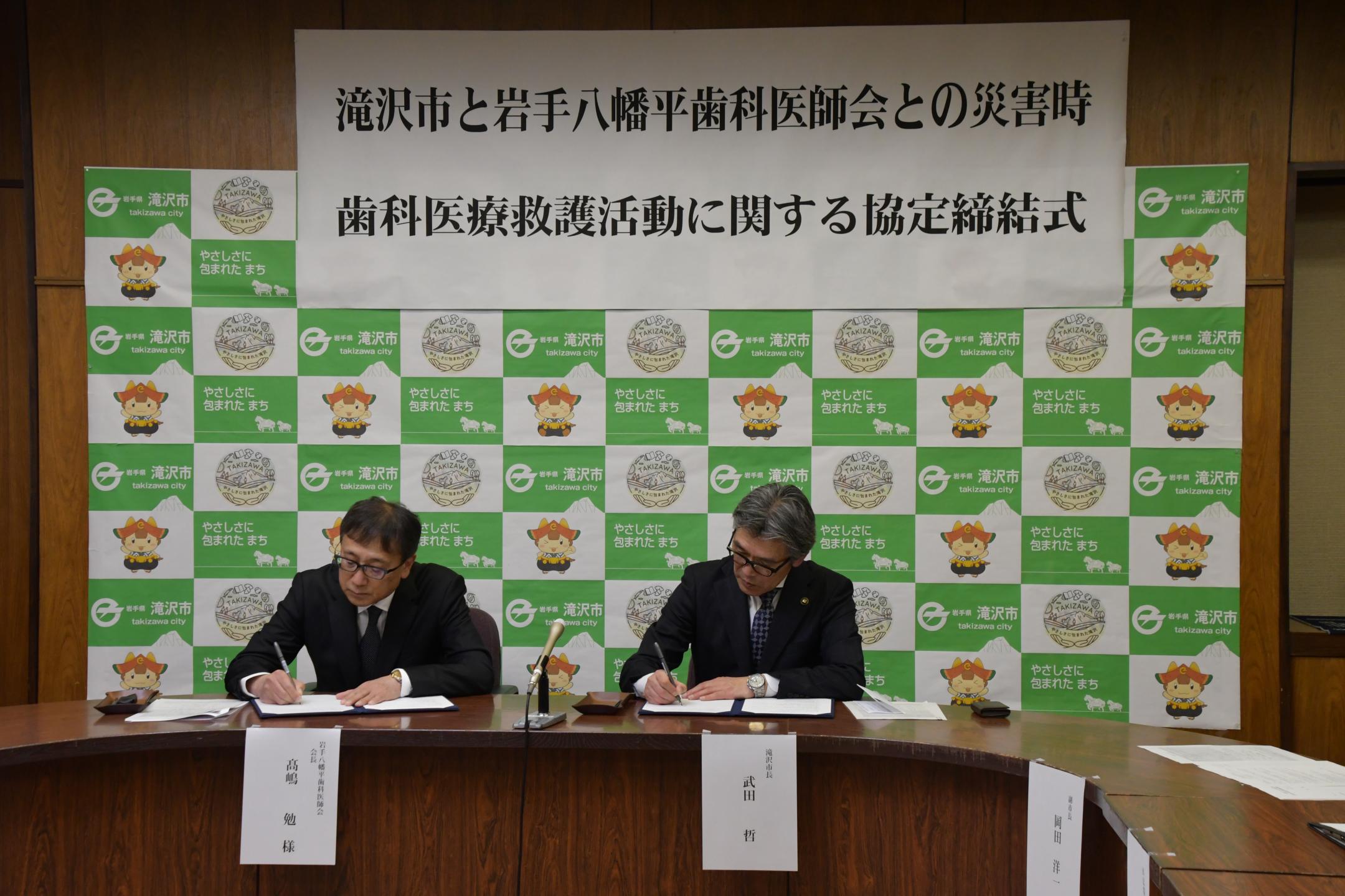 協定書に署名する髙嶋会長と市長
