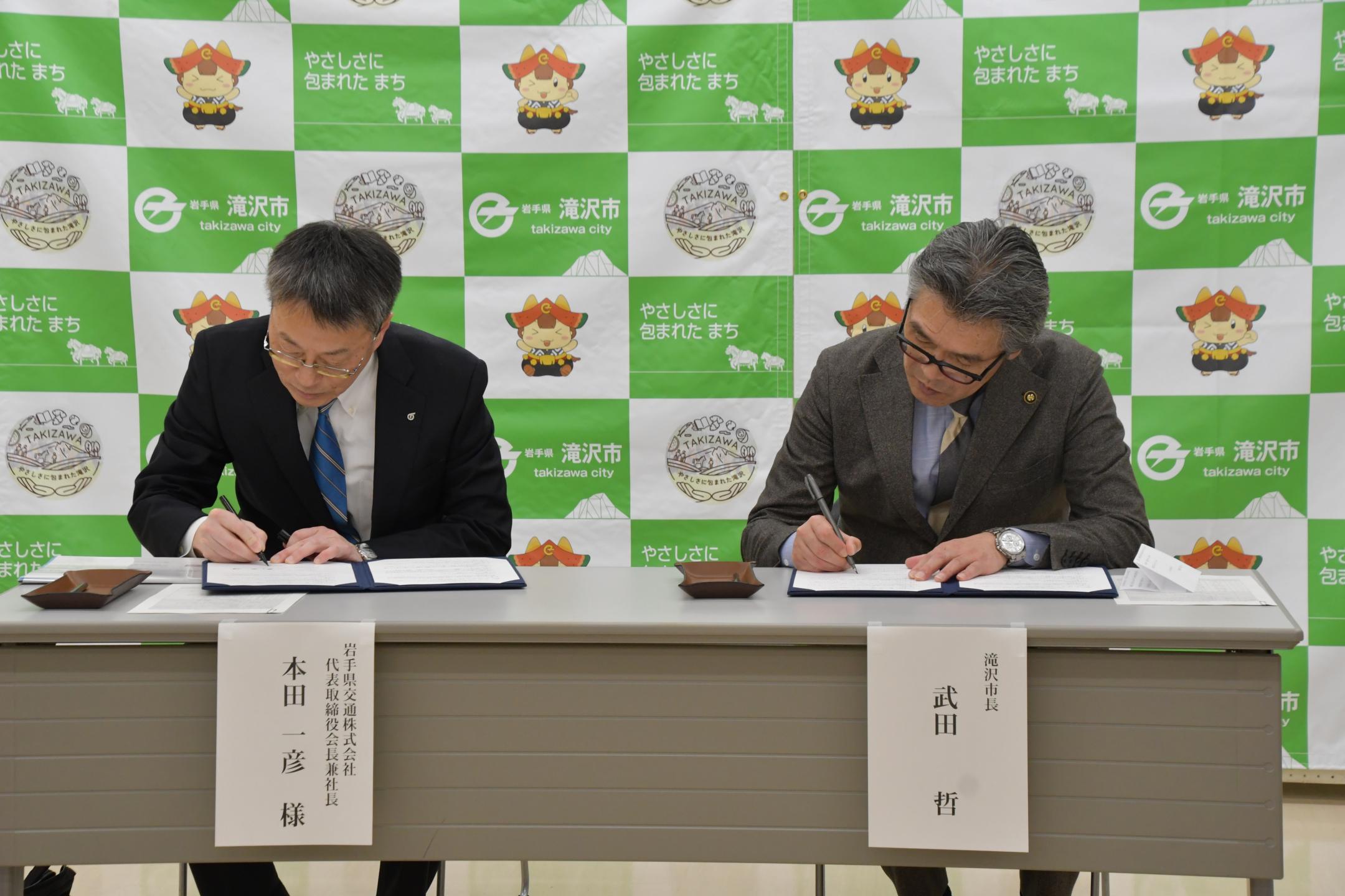 協定書に署名する本田社長と市長