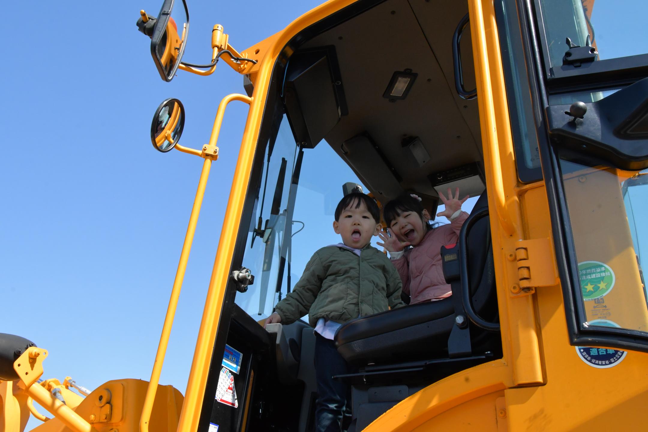 建設車両の運転席で記念撮影する子供たち