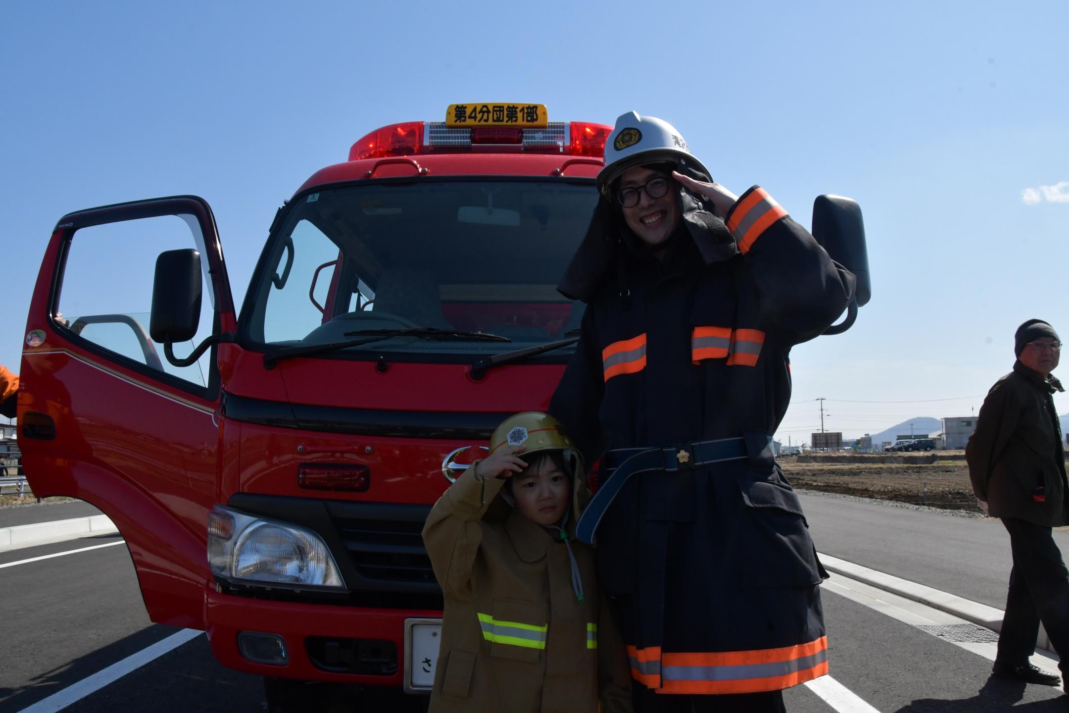 消防士の服を着て記念撮影する親子