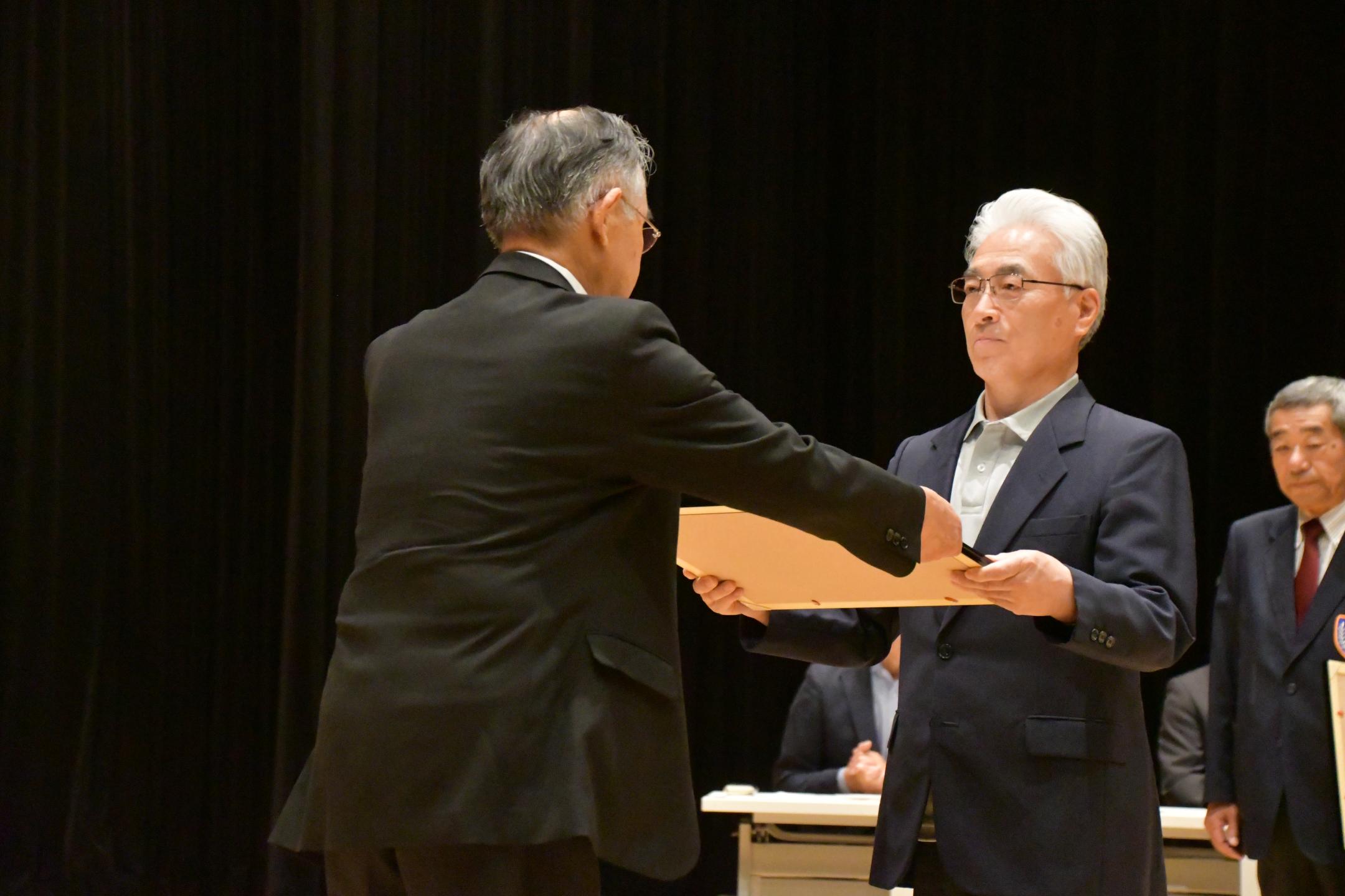 表彰状を受け取る束稲氏