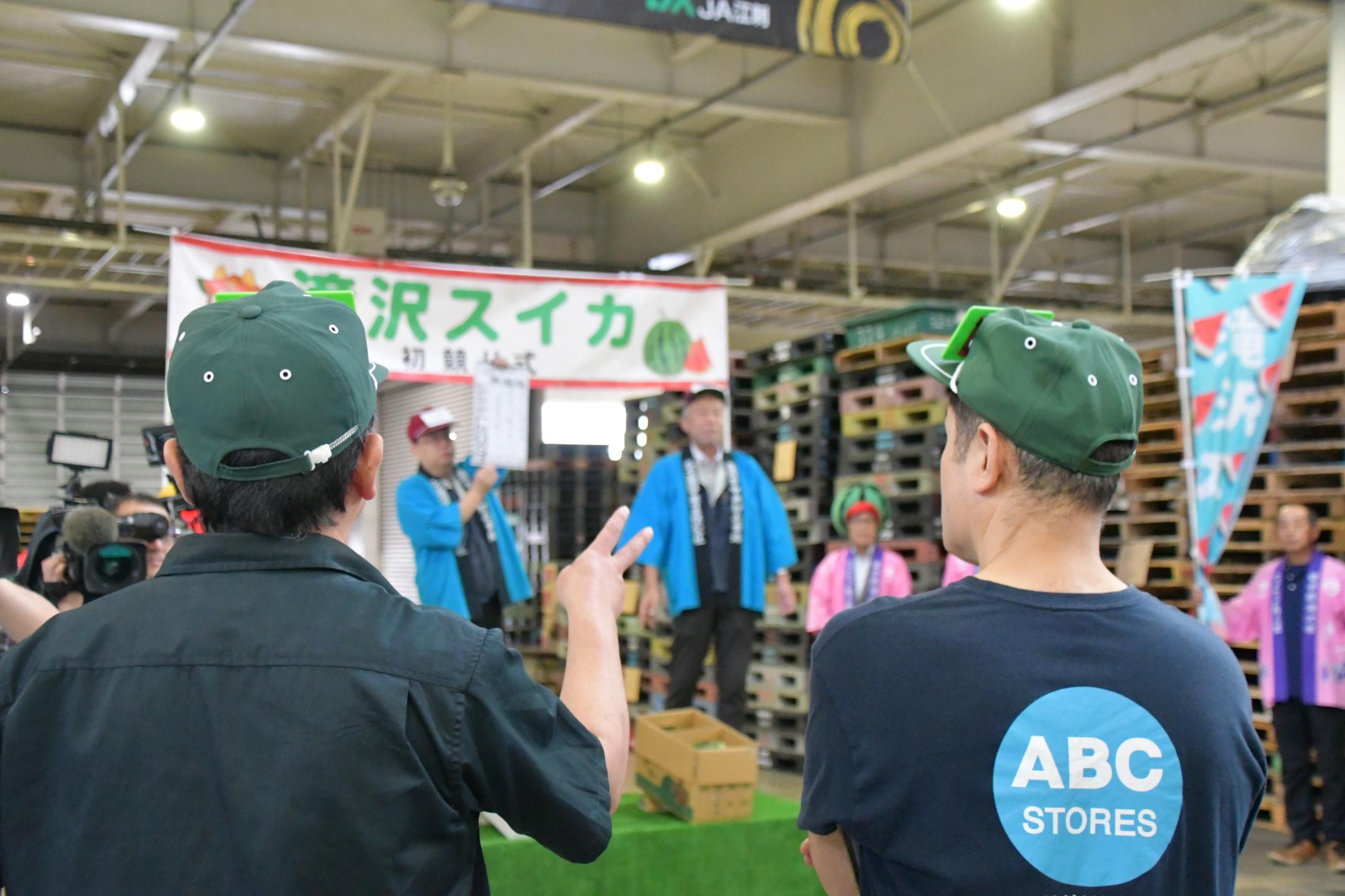 手を挙げて競りに参加する人の背中