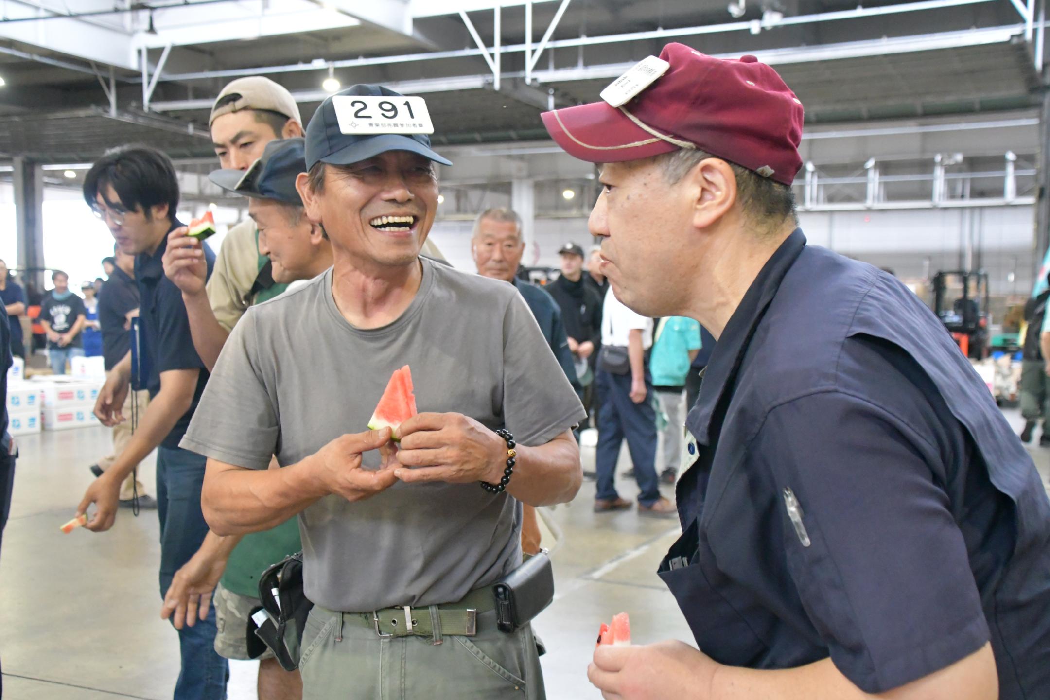 笑顔で試食用スイカを食べる競り参加者