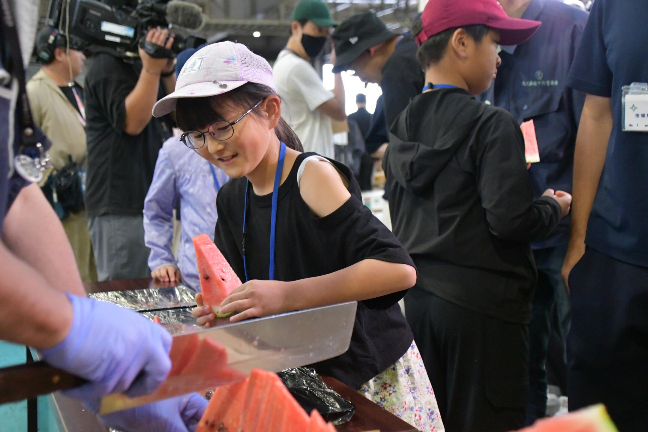 笑顔で試食用スイカを手に取る女の子