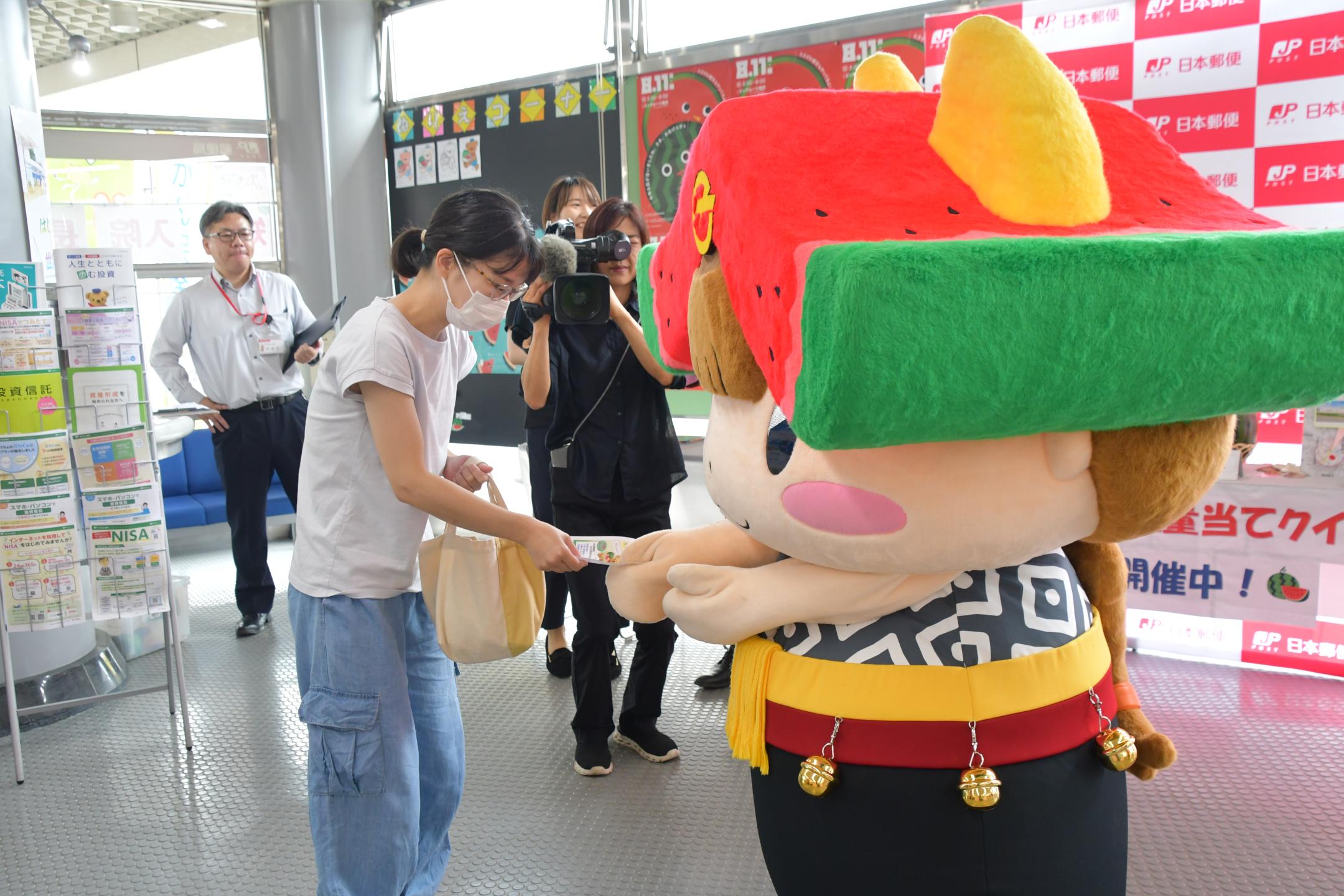 テレビカメラの前で来客にチラシを配布するちゃぐぽん