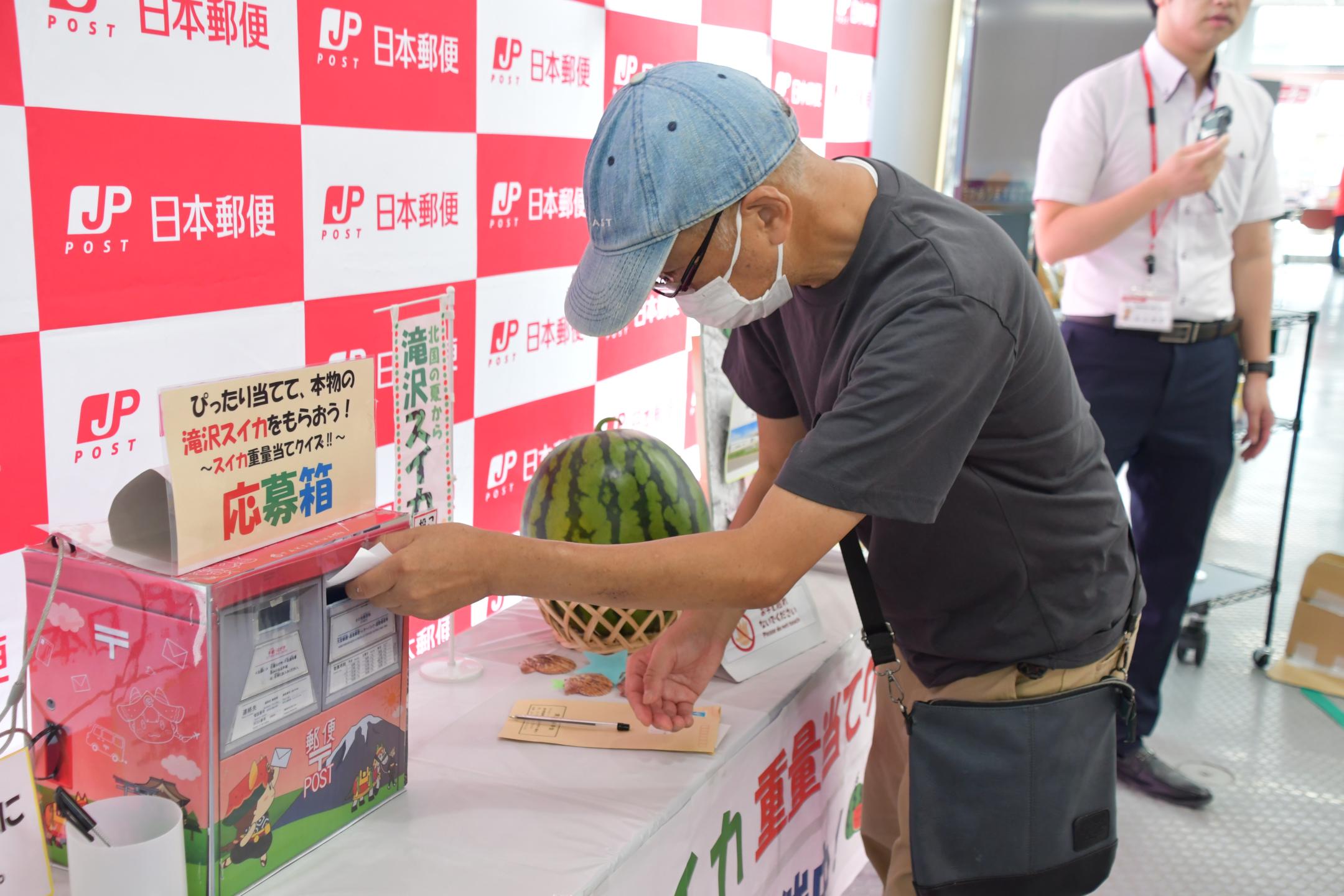 投票用紙を投票箱に入れる来客