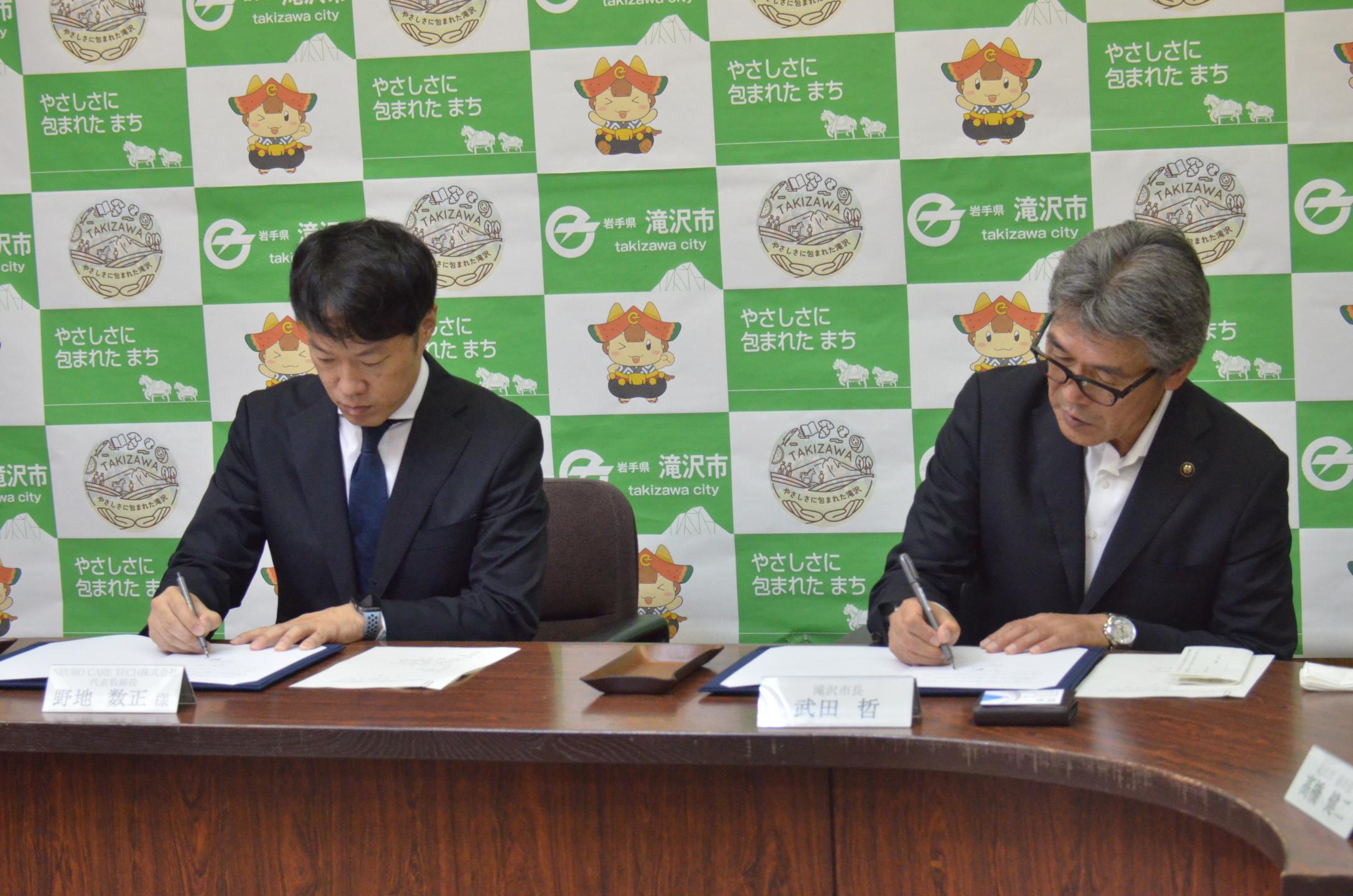 野地代表取締役と市長が協定書に著名