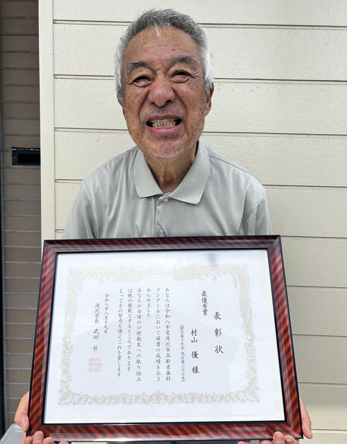 賞状を手に笑顔の村山さん