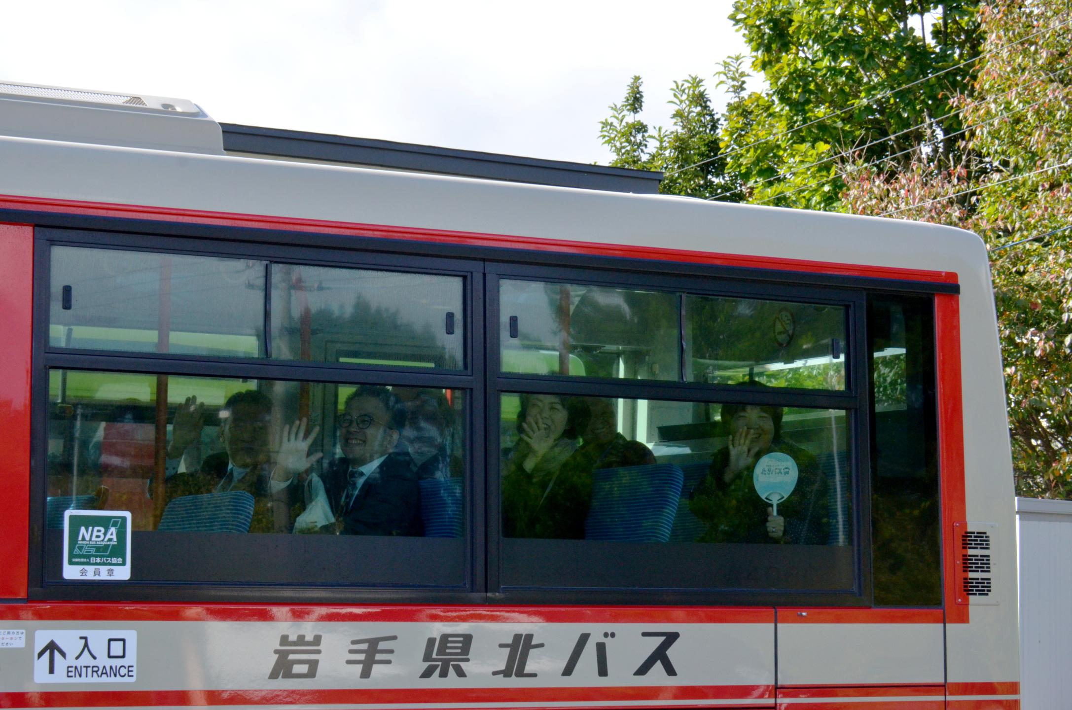 見送る職員へバス内から手を振る市民と副市長