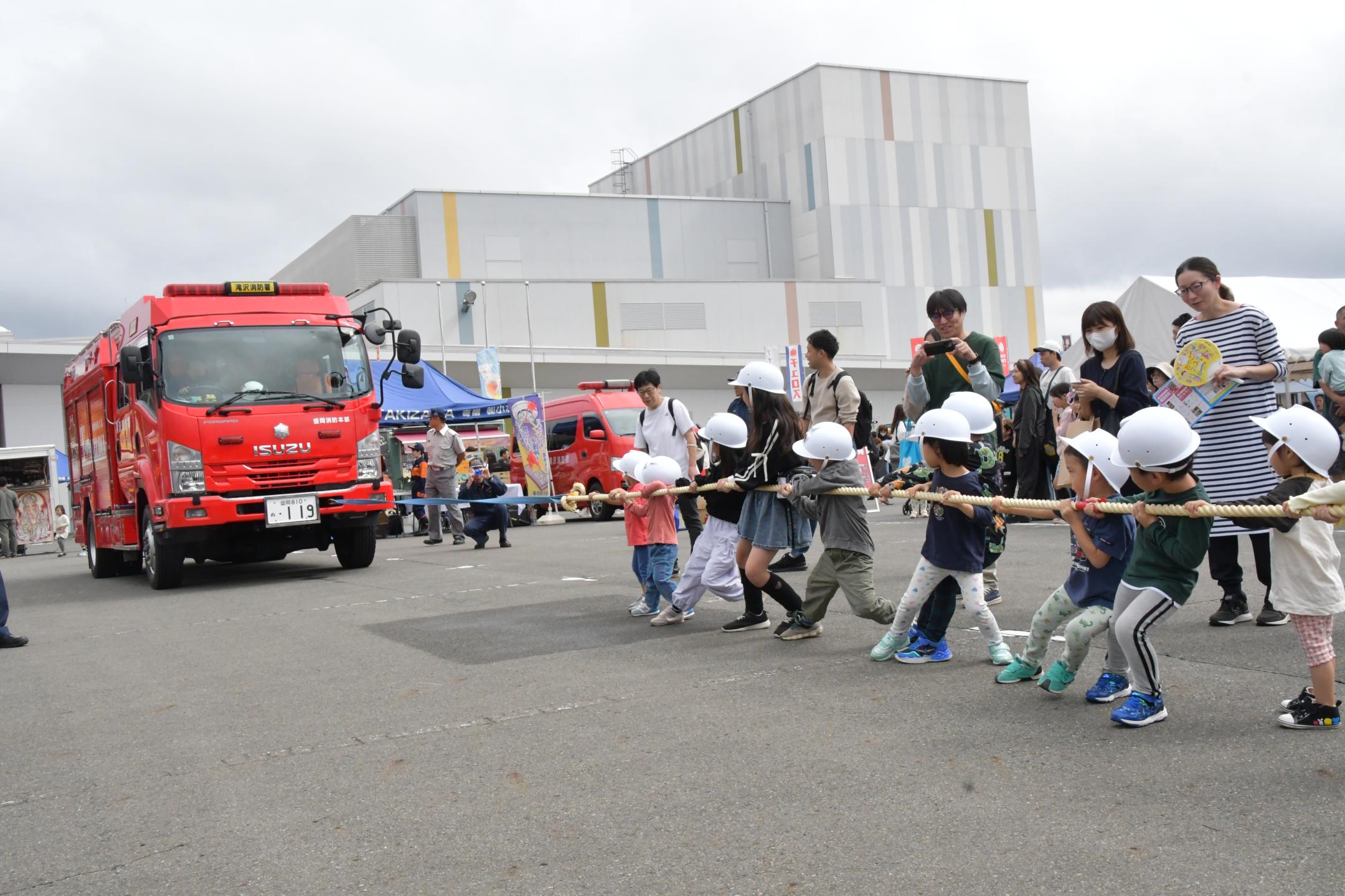 消防車両との綱引き体験をする子供たち