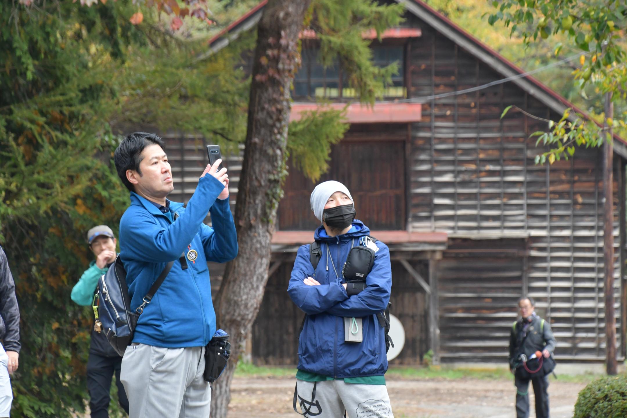 ガイドの説明を聞き文化財の写真を撮る参加者