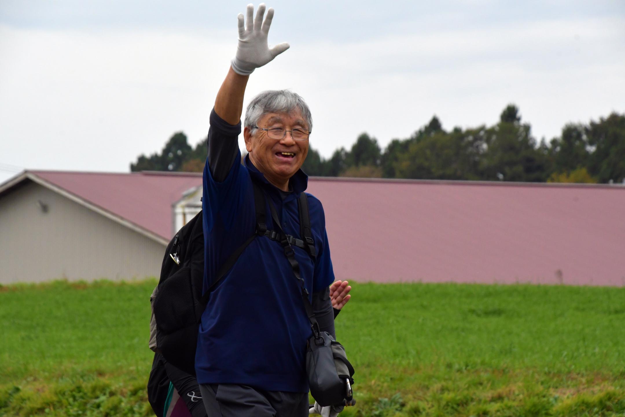 笑顔で手を挙げながら歩く参加者
